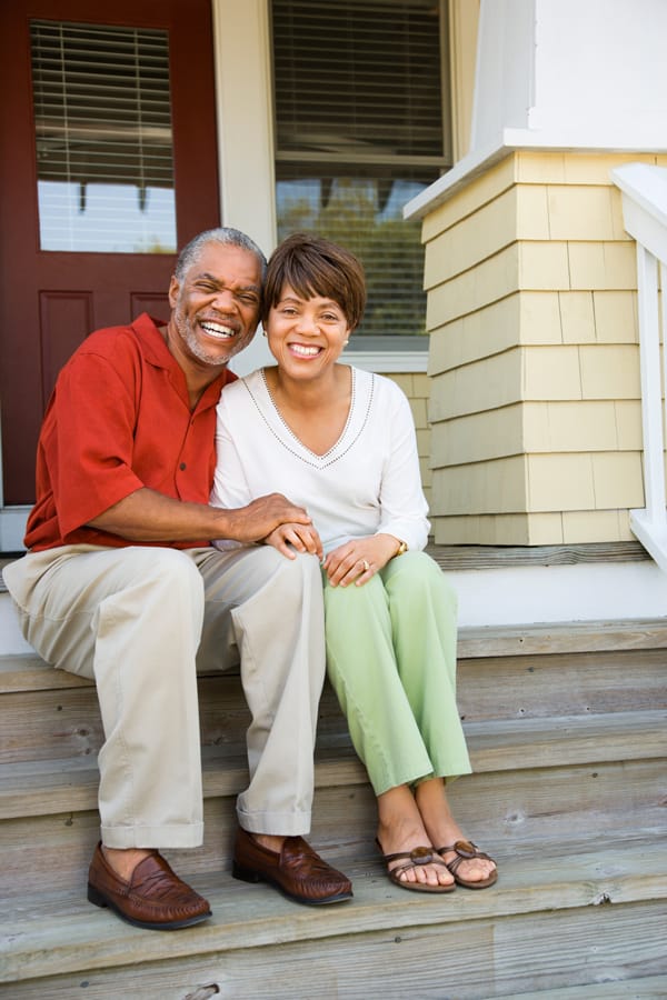 A couple sitting on steps embracing each other and smiling at the camera.